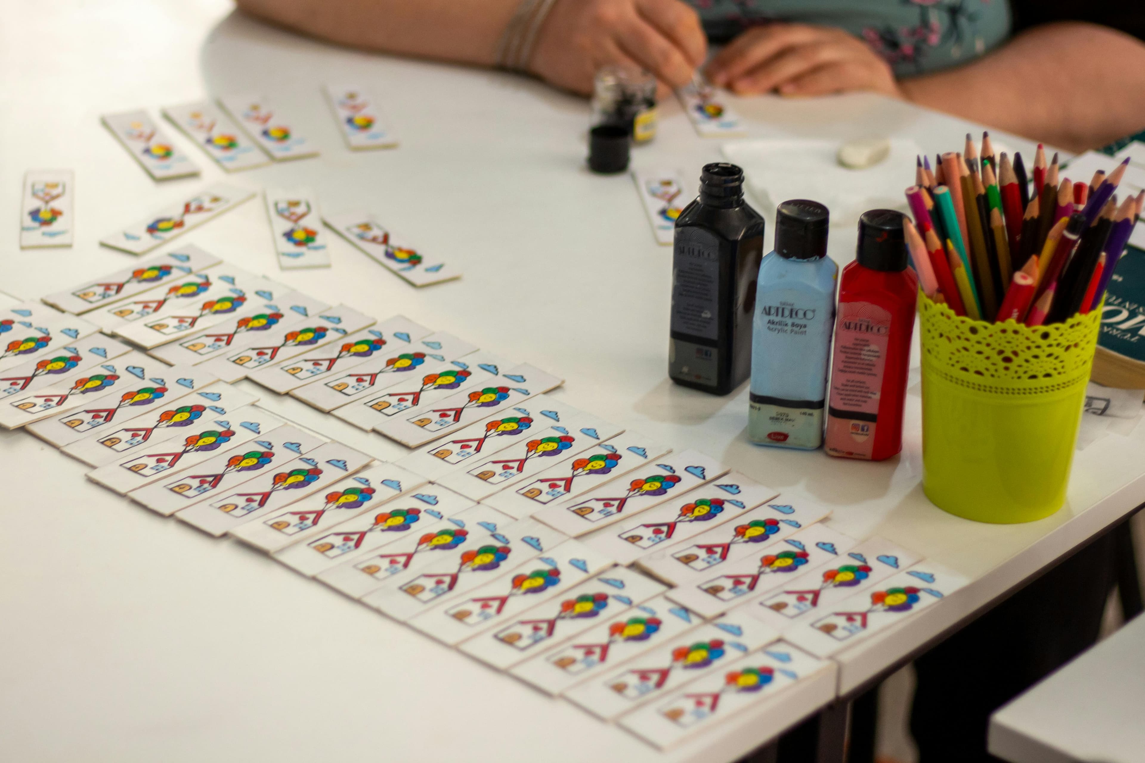 Painted playing cards and art supplies on a work table.