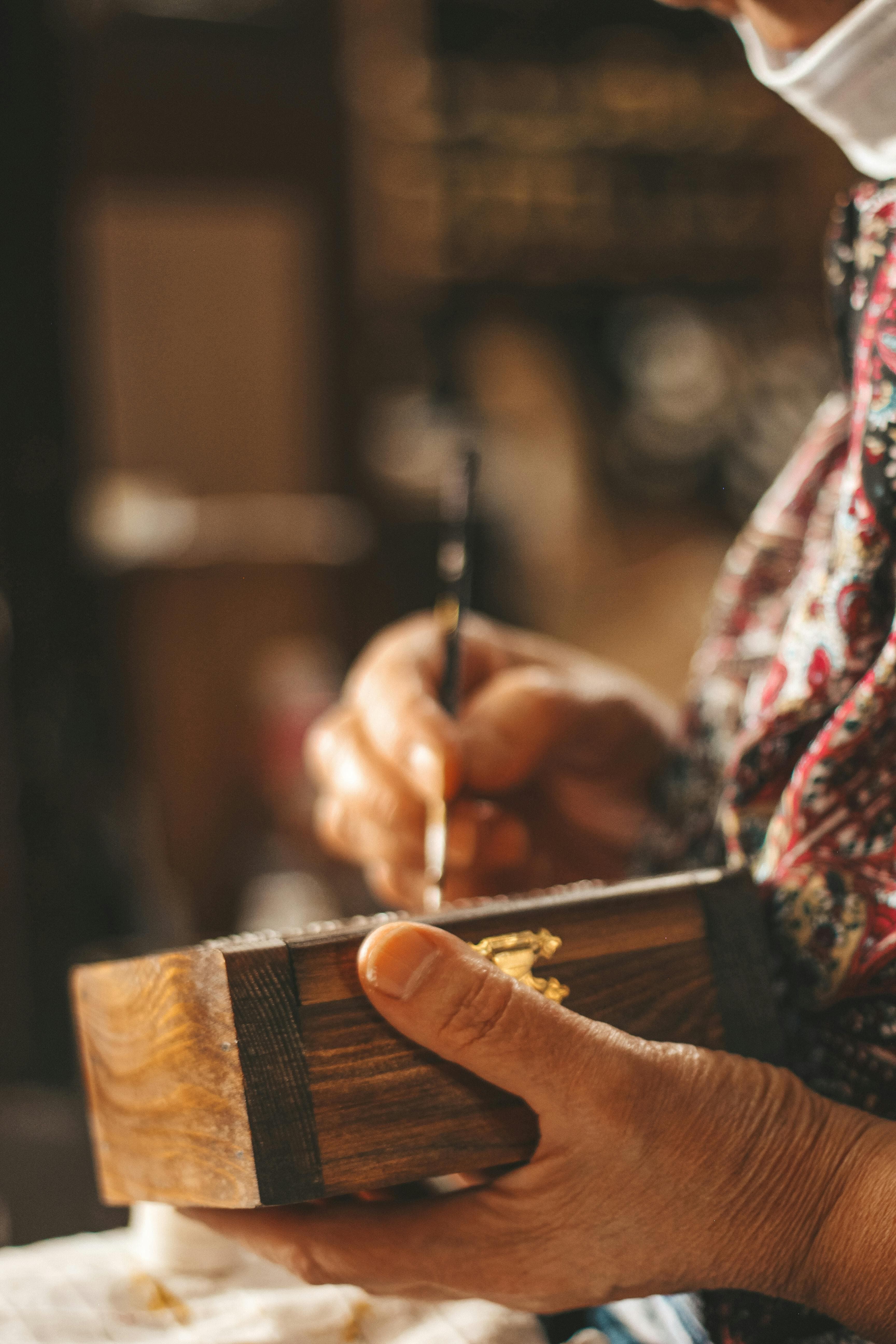 An artisan painting a small wooden box by hand.